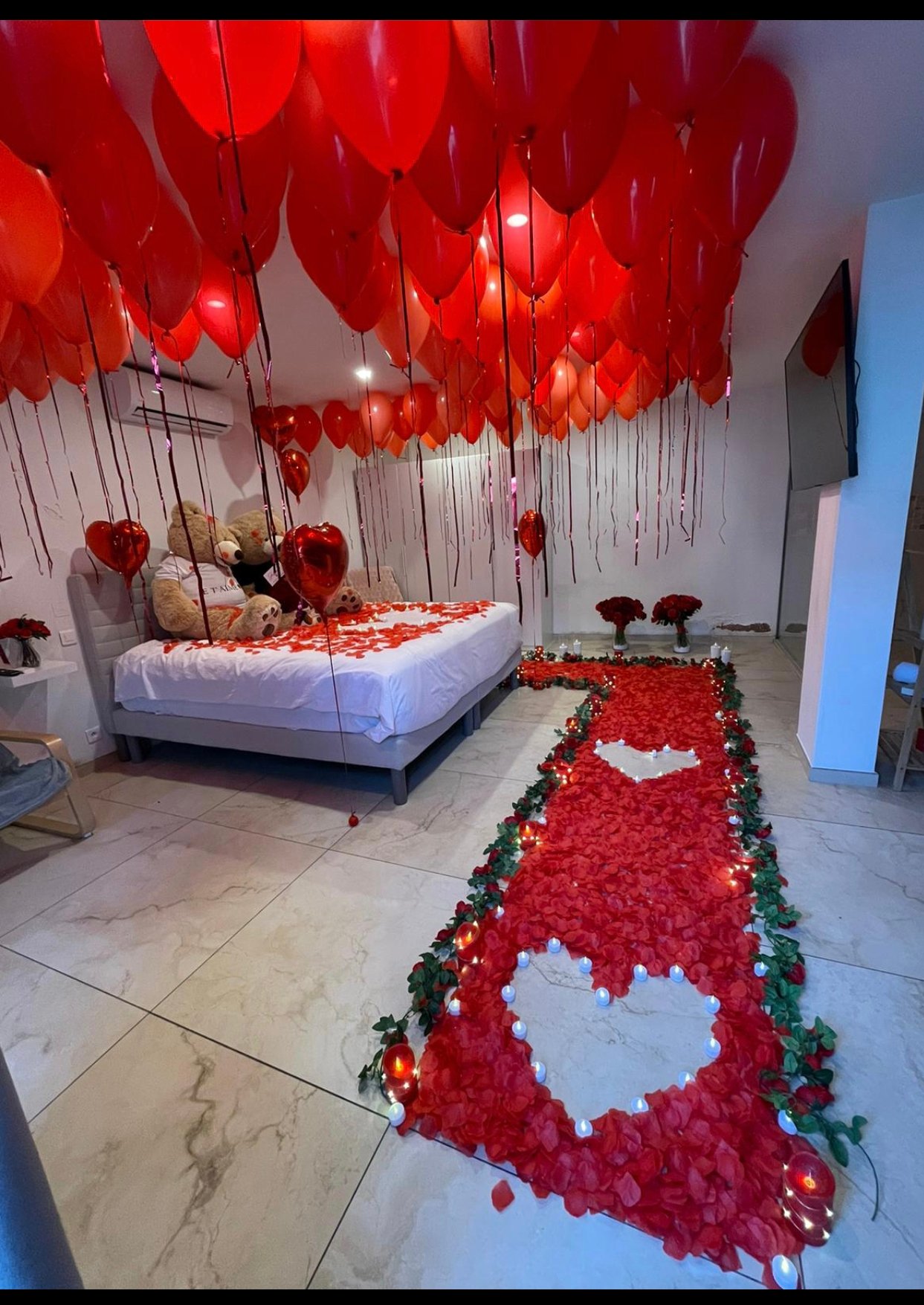 Décoration d’anniversaire romantique en chambre à Agde avec pétales et ballons